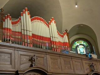 Large red and white pipe organ installed in a historic church. The ornate instrument stands above...