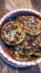 Grilled zucchini slices with garlic and pepper in rustic bowl.