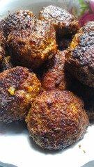 Crispy homemade meatballs with golden crust in white plate.