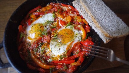 Hearty shakshuka with eggs, peppers, tomatoes, herbs, and bread.
