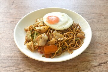 fried yakisoba Japanese noodles slice cabbage and carrot topping egg on plate  