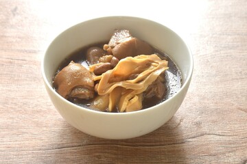 boiled slice Chinese bamboo shoot with pork leg and peanut in clear soup on bowl