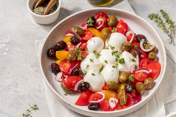 Сaprese salad with balls of Italian mozzarella cheese with ripe seasonal tomatoes, olives, fresh organic aromatic herbs and olive oil of high quality, balanced diet, Mediterranean diet