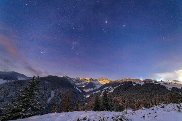 Starry night sky over the snow-covered Bavarian Alps in Sudelfeld, Germany