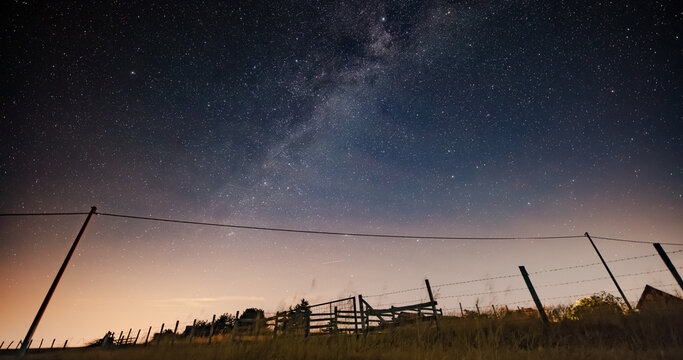 Milky Way stars and rural countryside silhouettes.