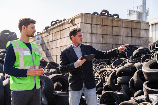 Businessman with colleague gesturing and discussing over rubber tires