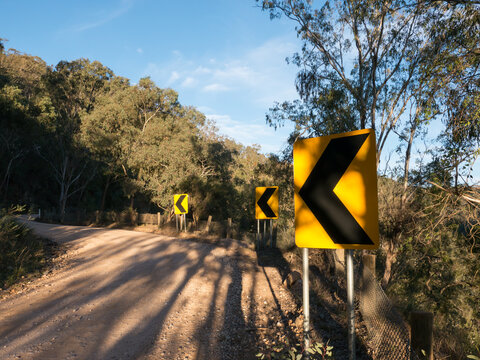 Sharp bend signs on narrow dirt mountain road