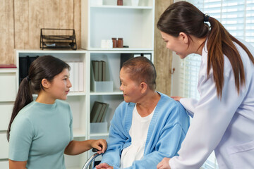 Asian doctor and young woman show kindness and encouragement to elderly woman in wheelchair,...