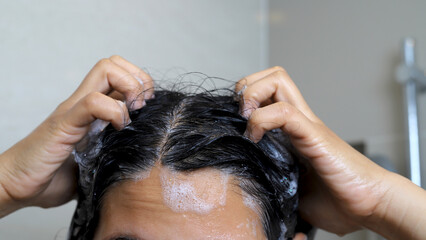 Naklejka premium woman is taking a shower and washing her hair in the bathroom
