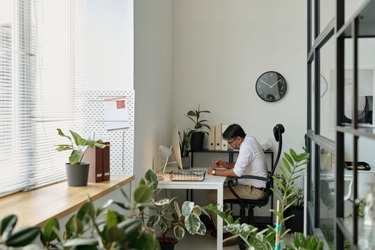 Person working at a desk in a modern office with plants and natural light