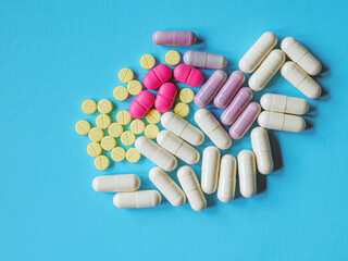 Assorted pharmaceutical medicine pills, tablets and capsules on blue background, top view
