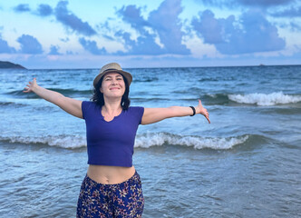 A joyful woman standing by the ocean with open arms, embracing nature and freedom, happy woman...