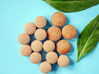 Brown herbal pill tablet on blue background