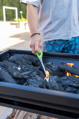 Man lighting charcoal on outdoor grill for barbecue