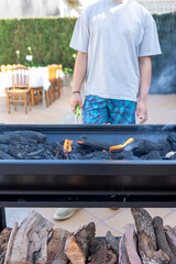 Man lighting charcoal in barbecue grill for summer party