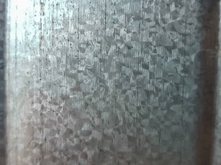 A detailed close-up of a galvanized metal sheet surface, showcasing its unique crystalline spangle pattern and textured background. Ideal for industrial, abstract, or material design projects.