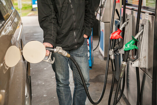 Man at petrol station filling up family car with fuel
