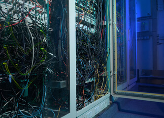 Complex network cables in a server room with blue lighting