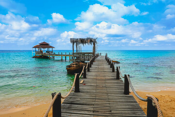 View of wooden bridge extending to the the beach in tropical island