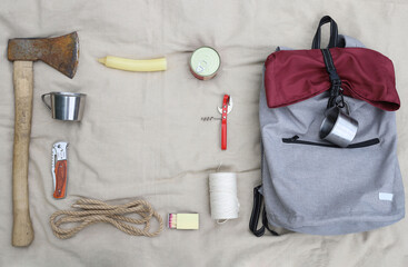 Hiking. Things and objects for tourism and survival in the forest or mountains. There is an axe, matches, canned food, rope, knife, backpack, headlamp, mugs