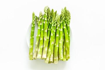 Fresh asparagus on plate on white background top-down copy space
