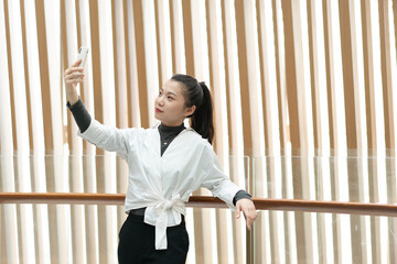 Beautiful woman leaning on railing using mobile phone