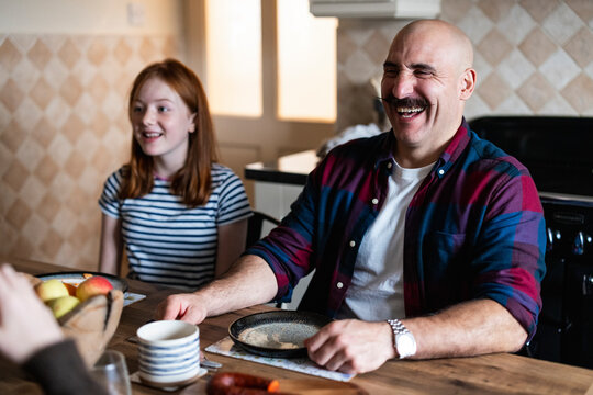 Happy man laughing with family during breakfast in the kitchen