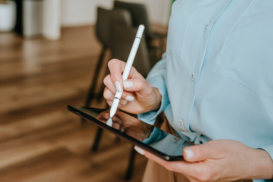 Businesswoman using a digital tablet with a stylus in an office setting