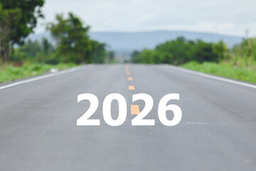 Empty asphalt road with 2026 text, green trees and mountain in background