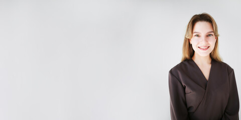 Smiling female cosmetologist in modern uniform on white background with copy space. Professional look and clean minimalistic style.