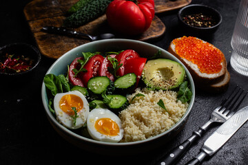 Couscous with boiled egg and vegetables in a plate on the table