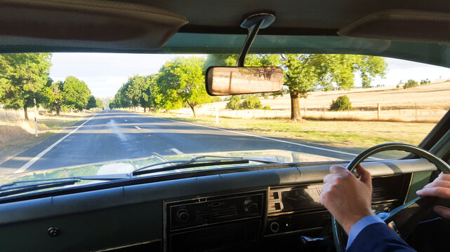 View out the front window of a classic car driving in the country
