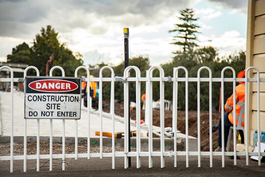 Danger construction site do not enter sign on a fence with construction site behind