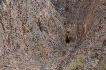 A rocky cliff wall with a small cave entrance in Charyn Canyon, Kazakhstan