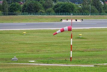 Red and White Windsock Beside a Grass Runway on a Clear Day in the airport