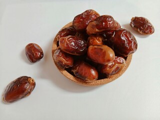 Dates in a glass bowl falling on a white background.