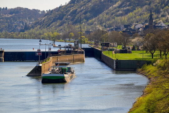 View of the St. Aldegund Mosel river lock with a barge navigating through.