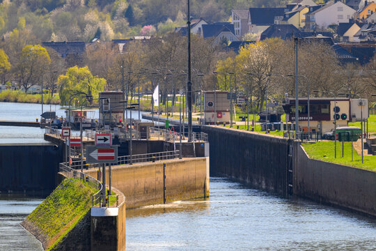 A close up view of the St. Aldegund Mosel canal lock system with surrounding greenery and buildings in the background.