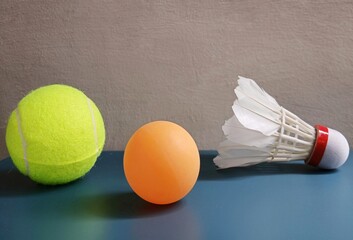 Tennis balls, ping pong balls and badminton shuttlecocks on a blue background. Sports that use rackets.