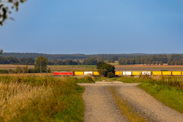 Fototapeta premium Panorama of a field, hilly landscape with a train in the distance