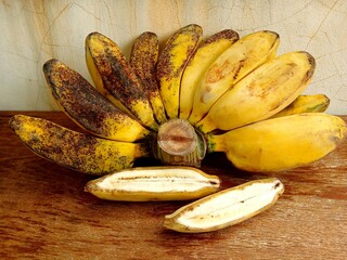 A cluster of ripe bananas is placed on a wooden table to be eaten. Sweet Gepok Banana. 