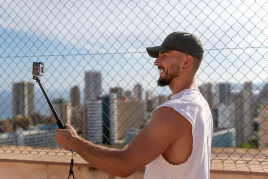 Influencer recording video content with action camera on selfie stick