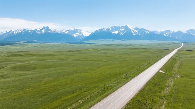 Aerial View of a Straight Road Stretching Towards Snow-Capped Mountains - Powered by Adobe