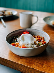 Fresh bowl of colorful rice and vegetables with poached egg at a cozy cafe