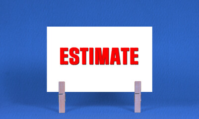 ESTIMATE Symbol. Concept words ESTIMATE on White Rectangle Paper Held by Wooden Clothespin Blue...