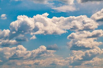 White textured clouds in a blue sky in warm light close-up, a heavenly landscape with clouds in the sky, clouds with sunny shades of warm light.