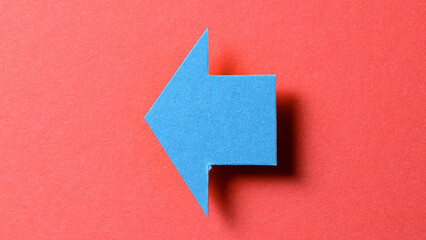 Blue blank paper cardboard arrow direction sign with shadow and copy space for text on red background, flat lay top view pointing symbol message backdrop