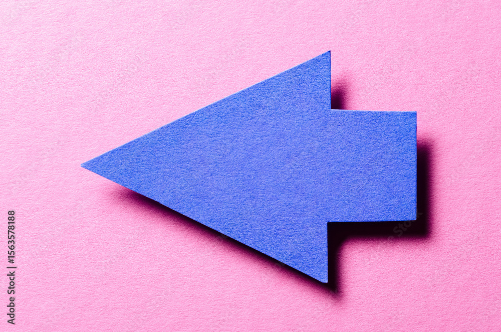 Fototapete blue cut out blank paper cardboard arrow direction sign with copy space for text on pink background,