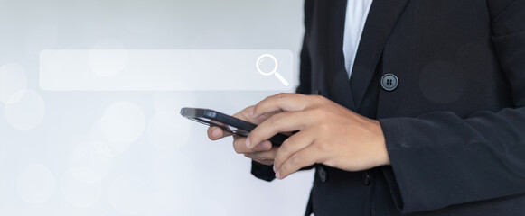 Businessman hand holding smartphone with search bar icon on screen, technology concept for online searching, digital marketing, and internet browsing, professional office background.