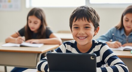 Smiling boy using a tablet computer in a classroom setting with other students studying